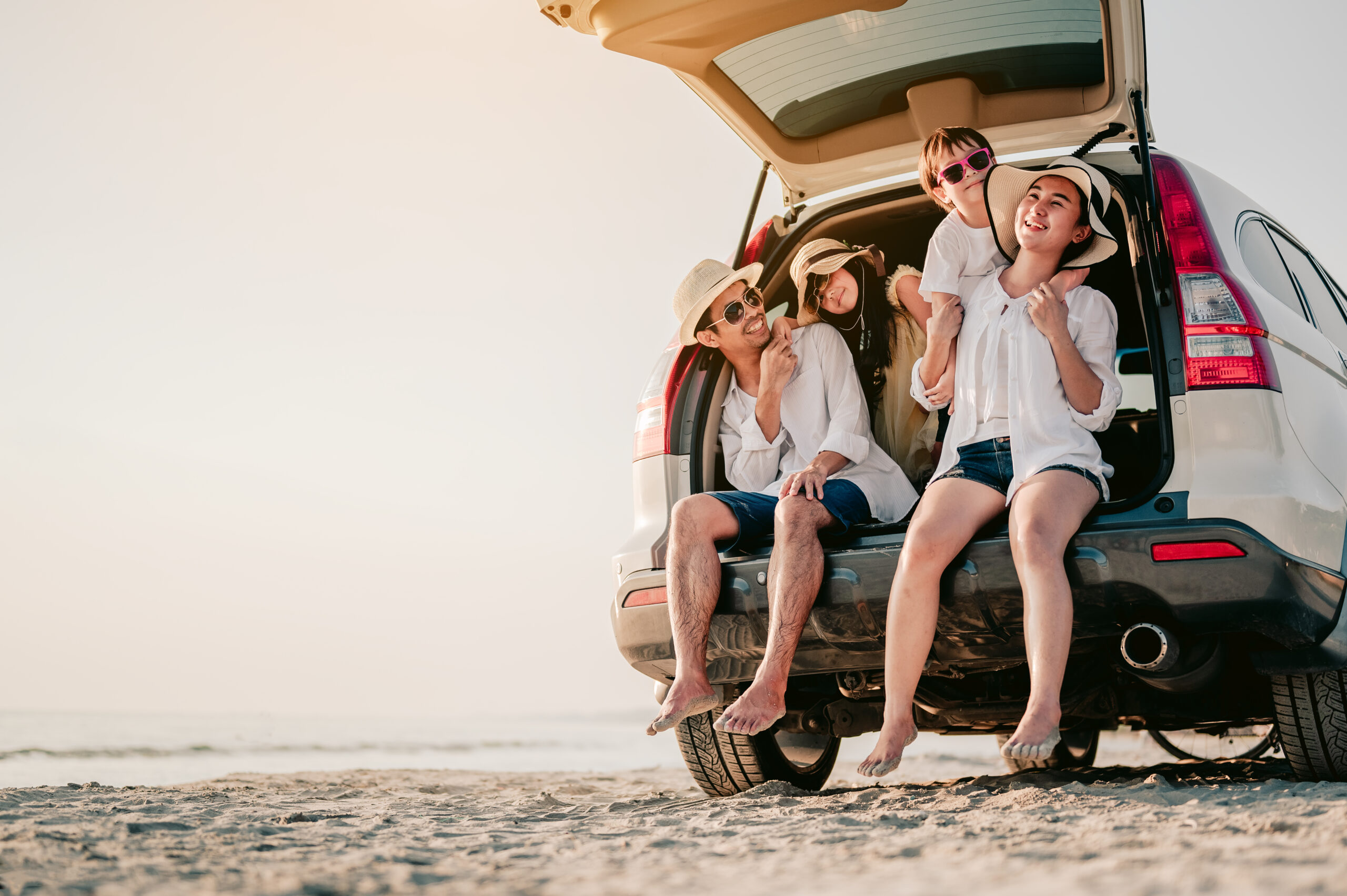 Happy asian family on a road trip in their car. Dad, mom and daughter are traveling by the sea. Summer ride by automobile.